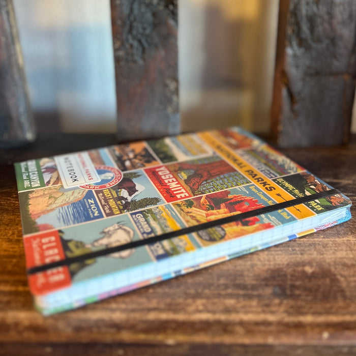 National Parks Vintage Notebook Large shown from a different angle with a vibrant collage cover on a wooden surface
