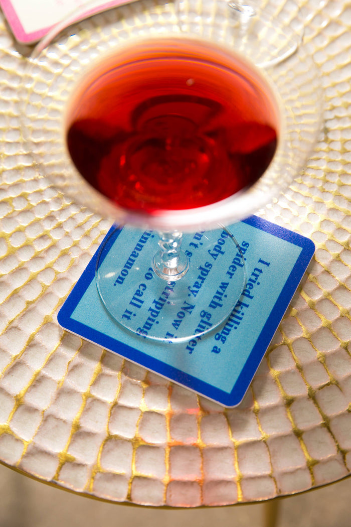 Red drink in glass on coaster, quote about killing a spider.