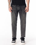 Martin Valen men's faded black jeans, front mid-shot showing straight leg and raw frayed hem