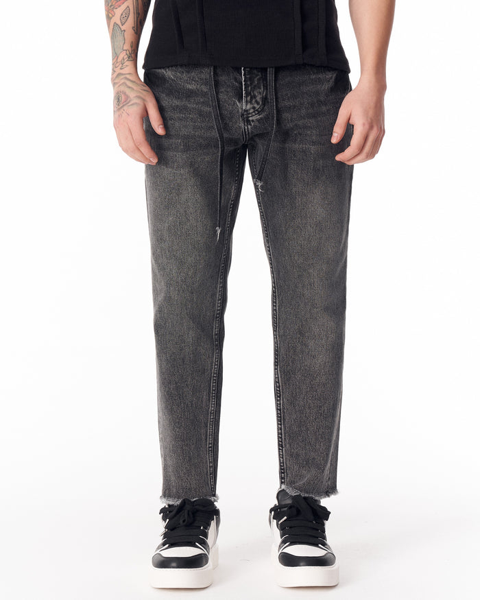 Martin Valen men's faded black jeans, front mid-shot showing straight leg and raw frayed hem