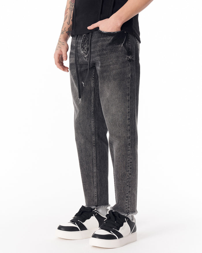 Martin Valen men's faded black jeans, three-quarter front view with hand in pocket and visible drawcord