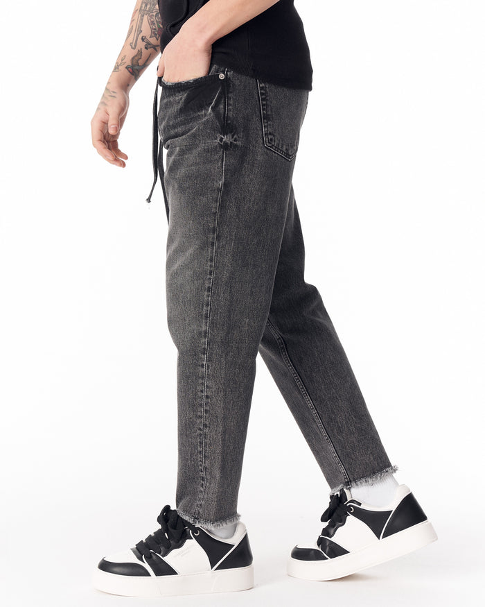 Martin Valen men's faded black straight-leg jeans, side close-up of waist and pocket showing drawcord and worn texture