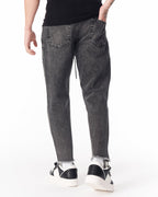 Martin Valen men's faded black jeans, close-up at ankle revealing raw frayed hem and black‑white sneakers