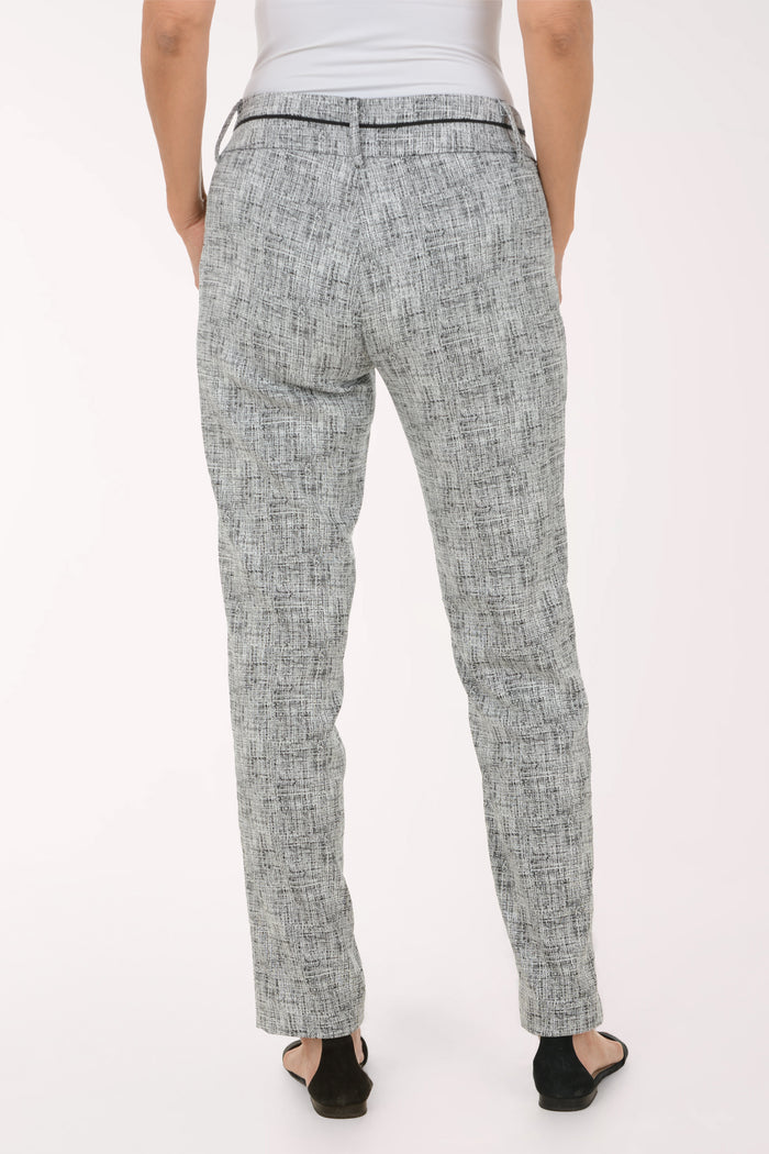 A model wearing a pair of slim-fit trousers in a gray and white textured tweed pattern, paired with black slide sandals against a plain white studio background.
