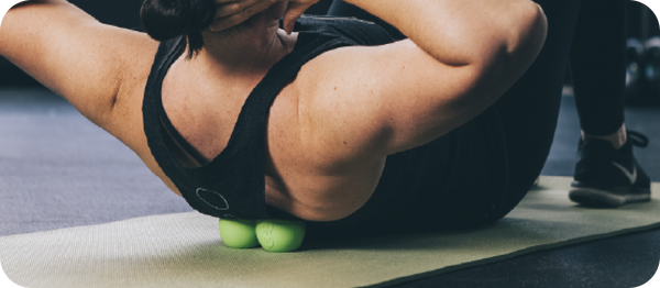 Person using a green RAD Roller Soft | RAD massage tool under their upper back while lying on a yoga mat, demonstrating muscle recovery and wellness care.