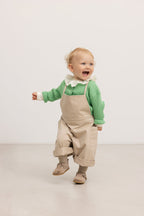 Beige selebukser til baby med seler, knapper og lommer ved bryst og ben