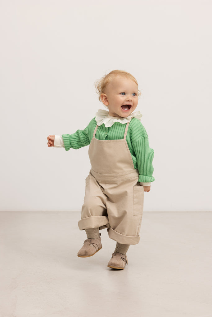 Beige selebukser til baby med seler, knapper og lommer ved bryst og ben