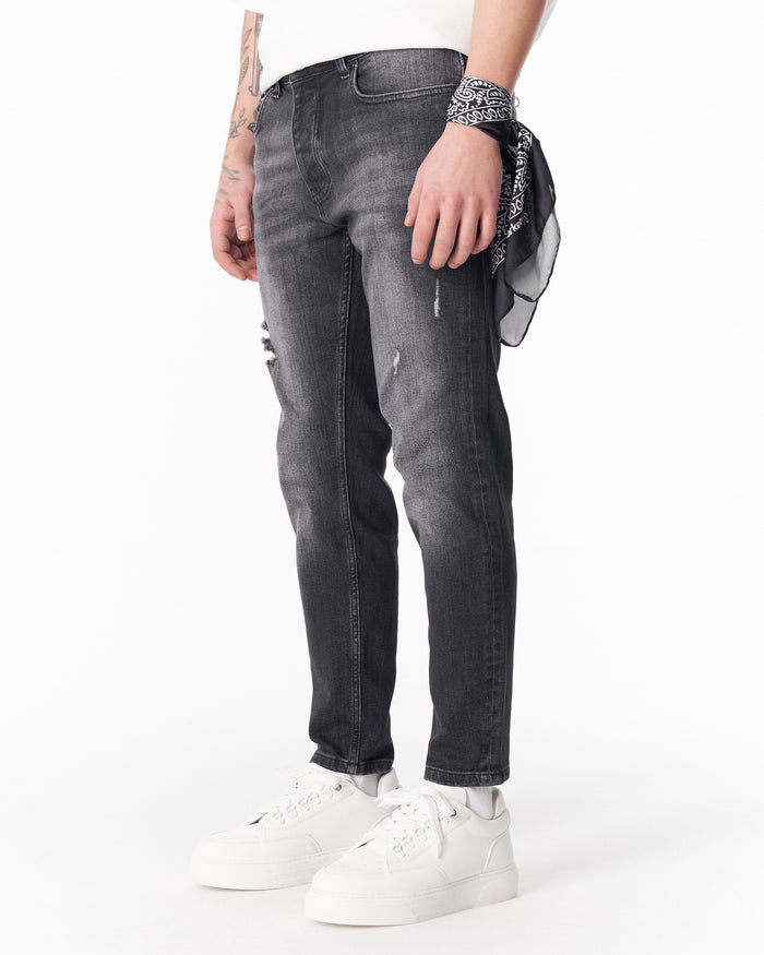 Martin Valen washed black slim-fit jeans, three-quarter front view showing distressed knee and wrist bandana