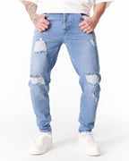 Martin Valen ripped slim-fit jeans in washed blue, mid-leg view with hands in pockets and knee distressing
