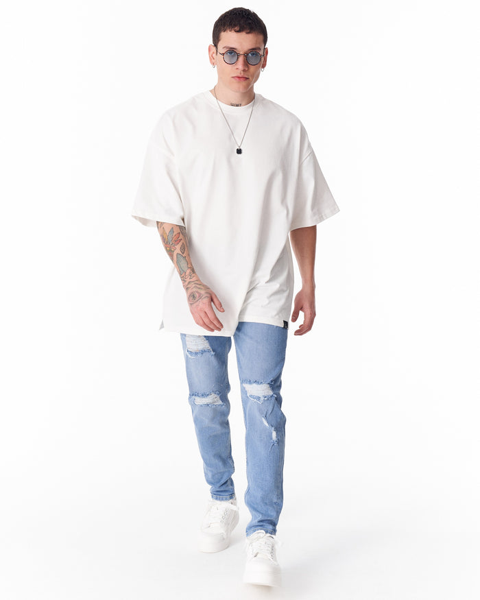 Martin Valen washed blue ripped slim-fit jeans, front view walking pose, distressed knee rips