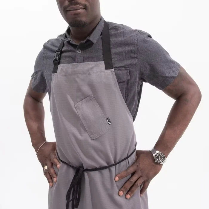 Man wearing a gray apron with black straps on a white background